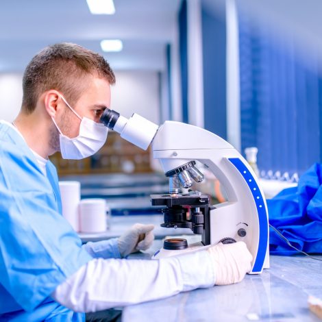 Scientist working in chemistry laboratory, examining samples at microscop